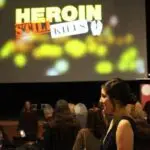 Crowd watching the video Heroin Still Kills at the release event