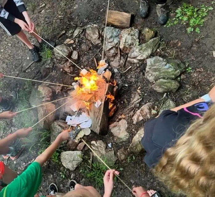 Group of kids roasting marshmallows over a small campfire